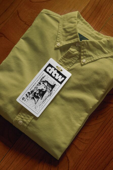 Lime green button-up shirt with black hang tag mockup displayed
