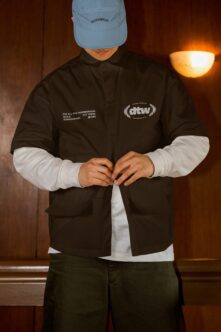 Black coach jacket with embroidered logo worn over white long sleeve shirt
