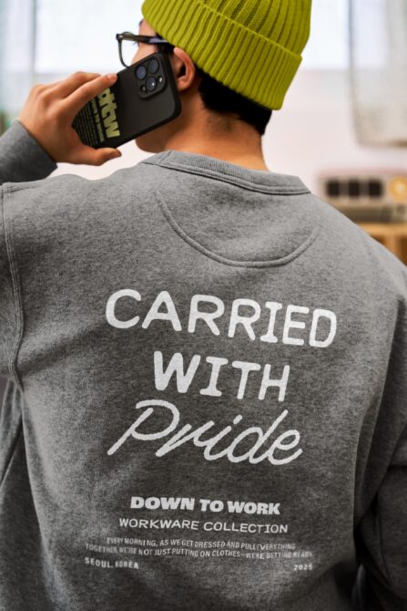 Guy in lime beanie holding black phone case showing back print of gray crewneck