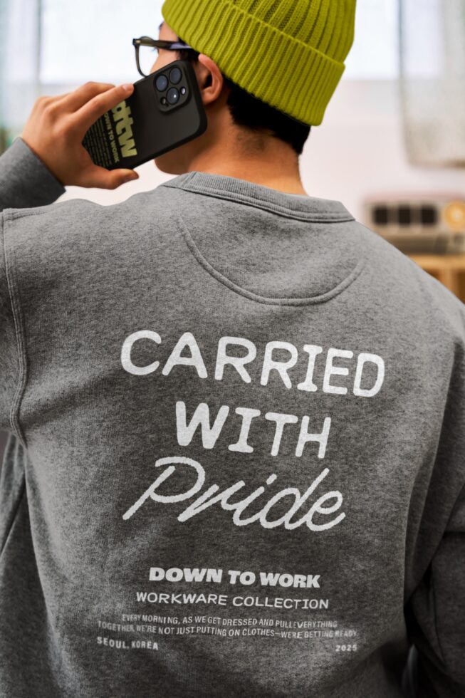 Guy in lime beanie holding black phone case showing back print of gray crewneck