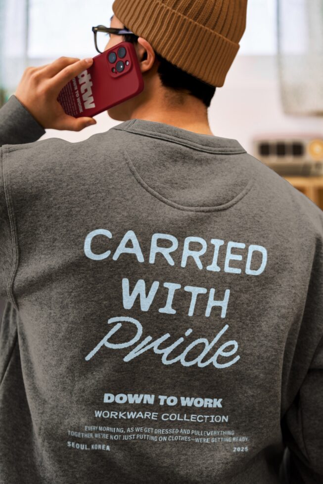 Back view gray sweatshirt with script text, tan beanie, holding burgundy phone
