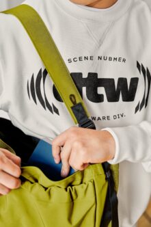 Lime green shoulder strap with black clasp on white sweatshirt with graphic logo