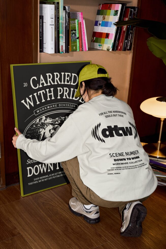 Person crouching holding black poster with cream workwear division logo