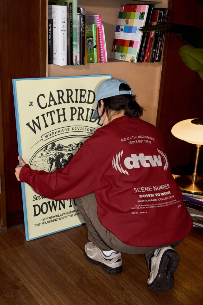 Person in burgundy jacket holding cream poster with Carried with Pride design mockup