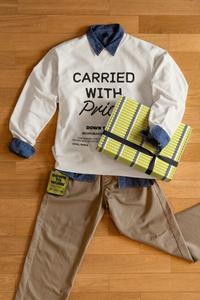 Cream sweatshirt with Carried with Pride text showing neon yellow striped box mockup flat lay