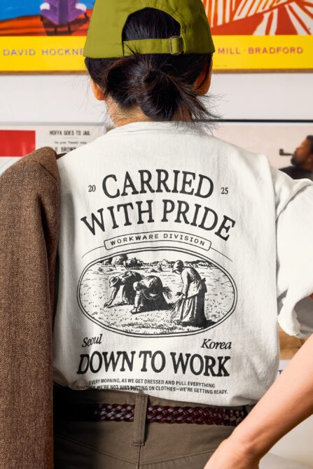 Cream tee showing Carried With Pride design featuring engraved figure illustration