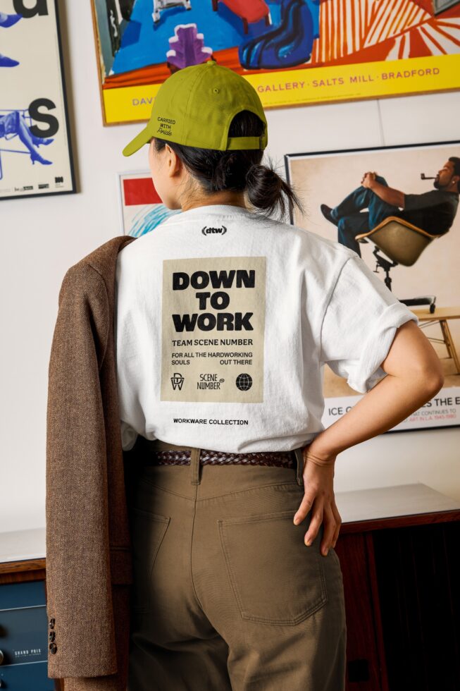 White tee with beige back print reading Down To Work over cream colored square patch