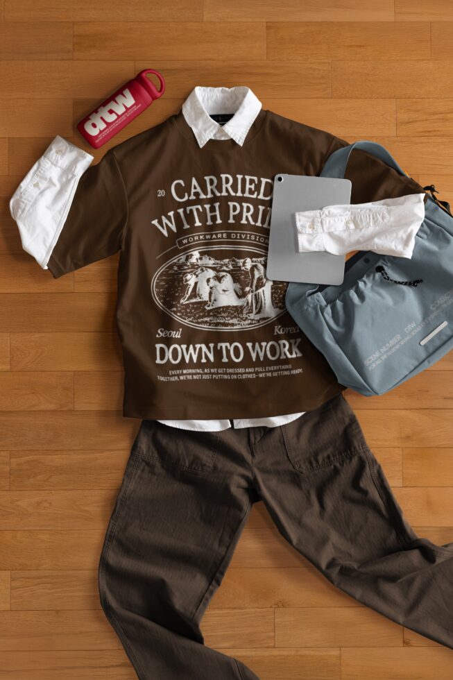Complete outfit flat lay with brown tee, dark pants, bag, tablet, tumbler, cap