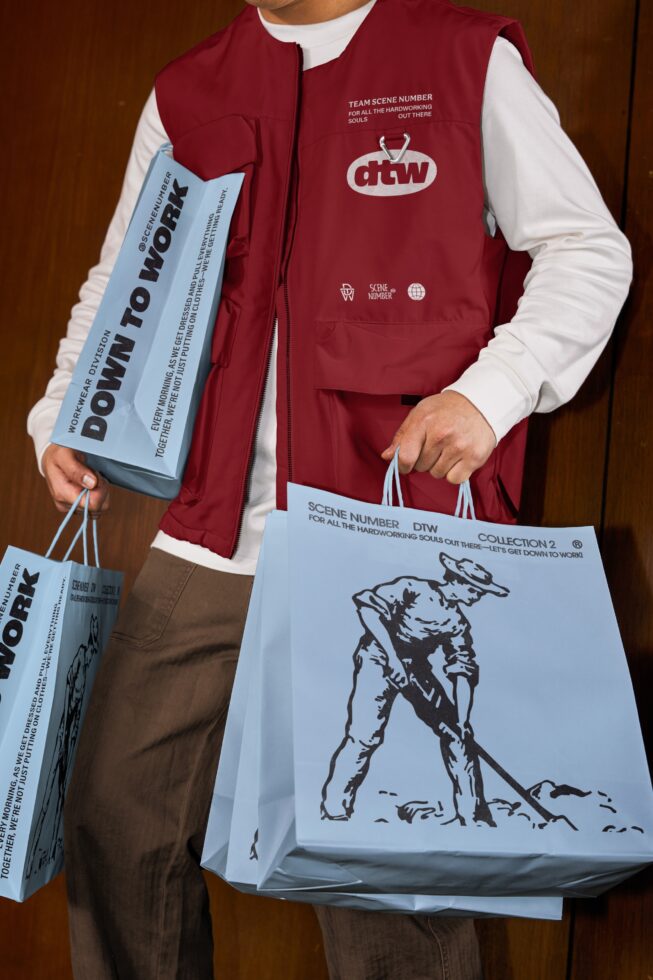 Burgundy puffer vest worn over white shirt, holding light blue paper bags with model showing lookbook