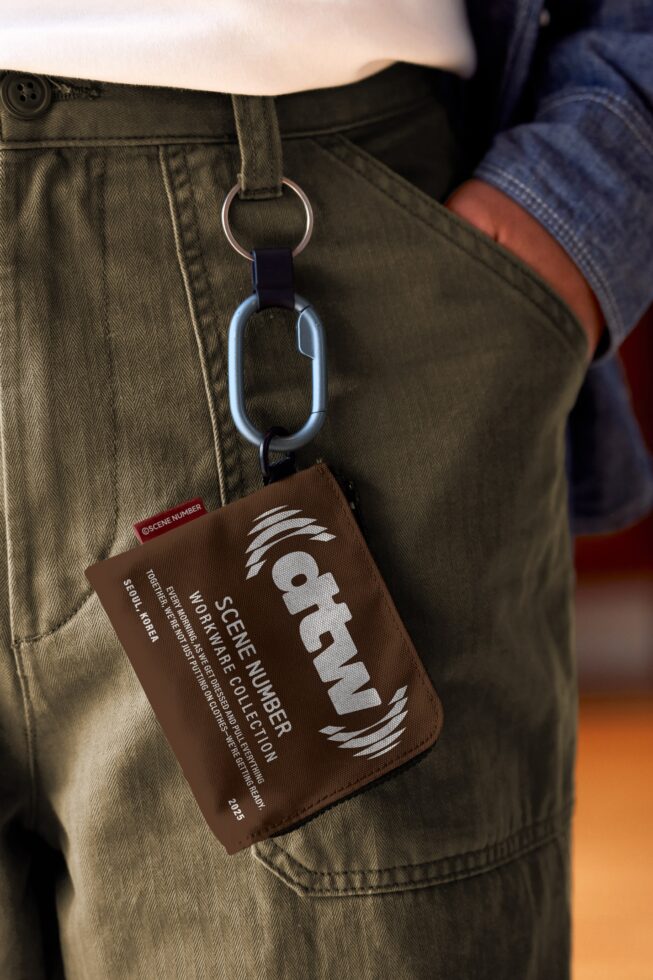 Brown fabric keychain tag hanging from olive pants with carabiner