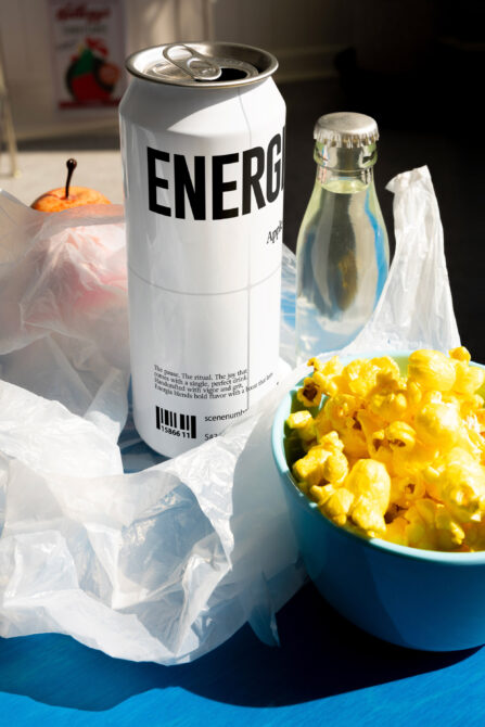 White Energia can on blue surface with snacks beside glass bottle