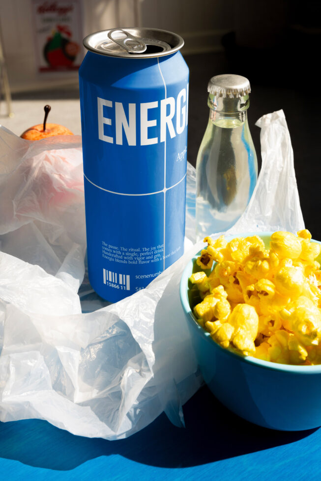 Blue Energia branded can with popcorn bowl beside glass bottle