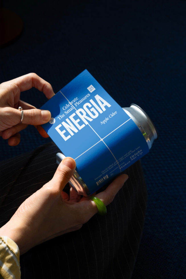 Hand holding blue ENERGIA can mockup with customizable label grid layout