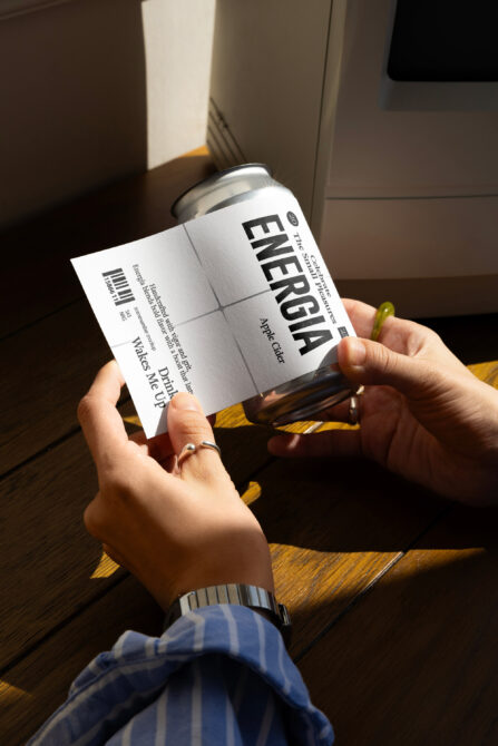 Hands holding white can label mockup pulled back from aluminum can, showing label flexibility