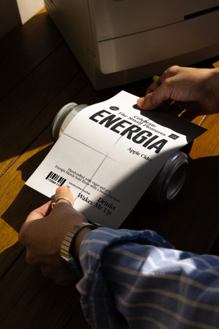 Hand pulling white can label from aluminum can mockup, showing wrappable label design