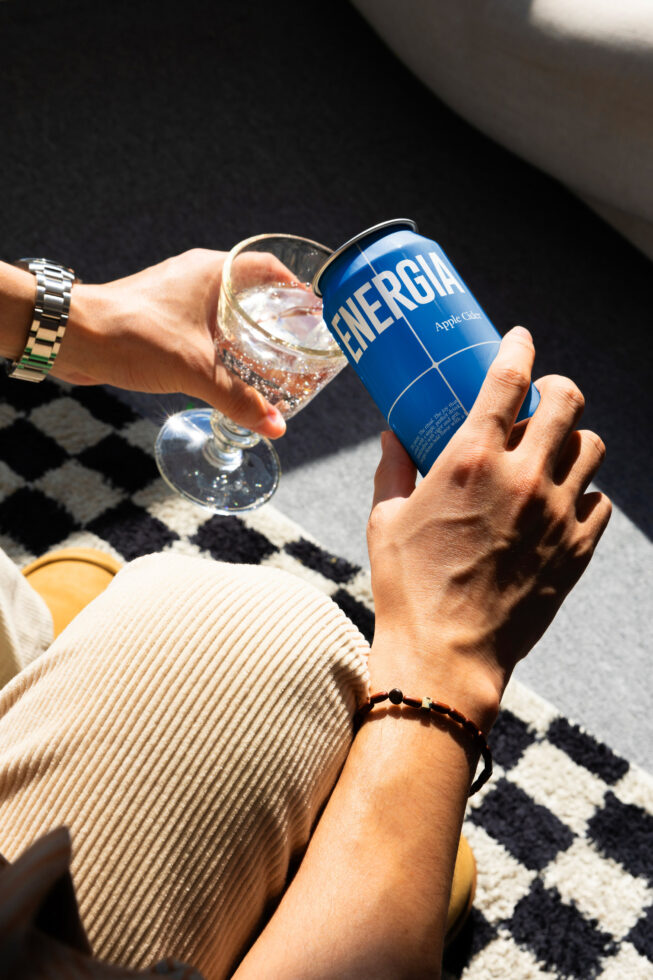 Blue aluminum can next to sparkling beverage in glass on patterned blanket