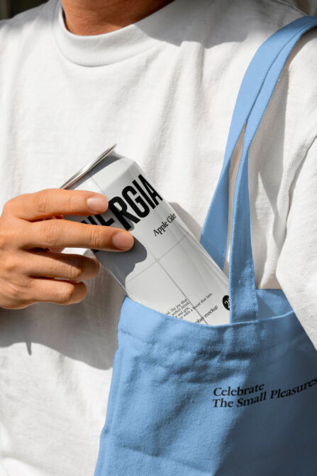 Person in light shirt pulling white beverage can from blue canvas shoulder bag