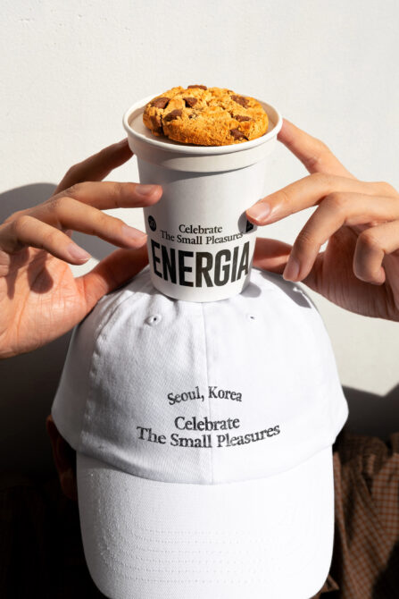 Hands holding white cup with cookies, matching white branded cap