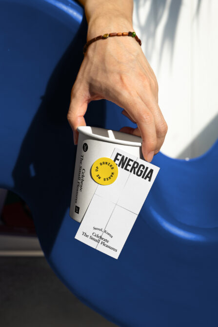 Hand holding drink carton with yellow circle label over blue background