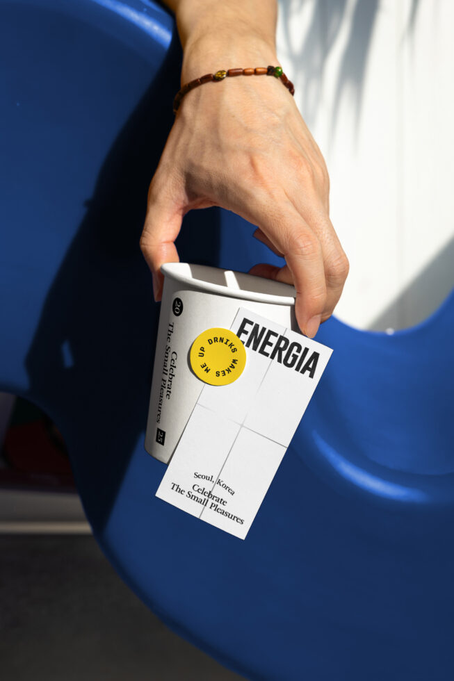 Hand holding drink carton with yellow circle label over blue background