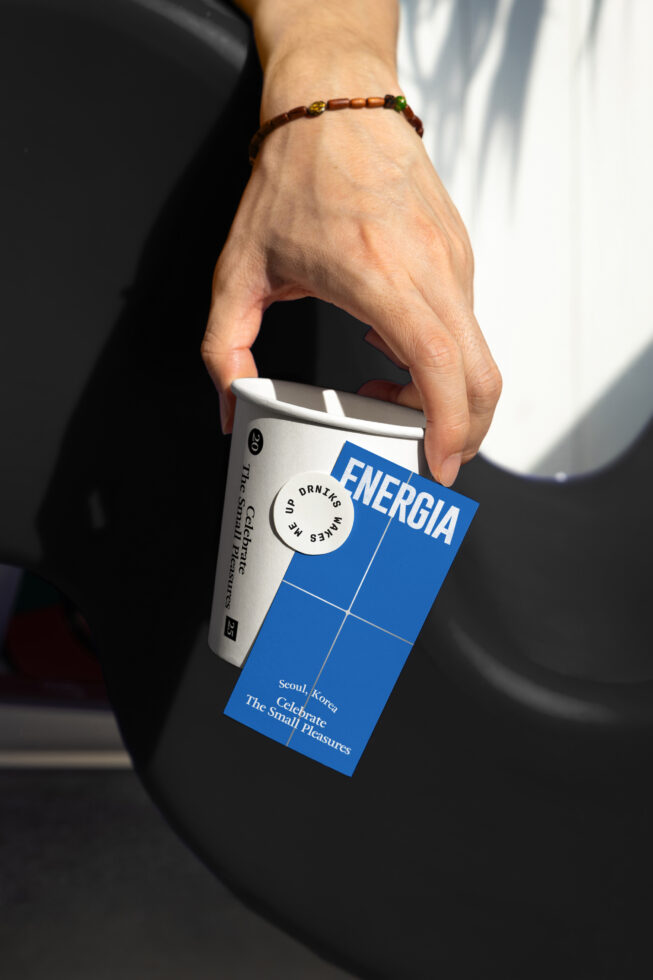Hand holding takeout cup with blue sticker next to blue product packaging