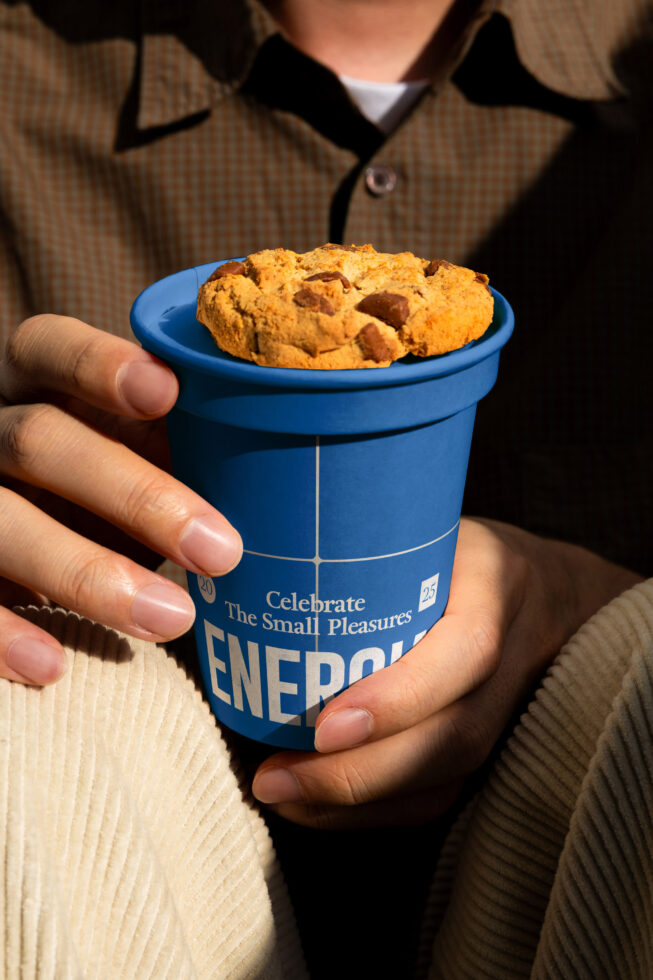 Hand holding bright blue paper cup with chocolate chip cookies inside