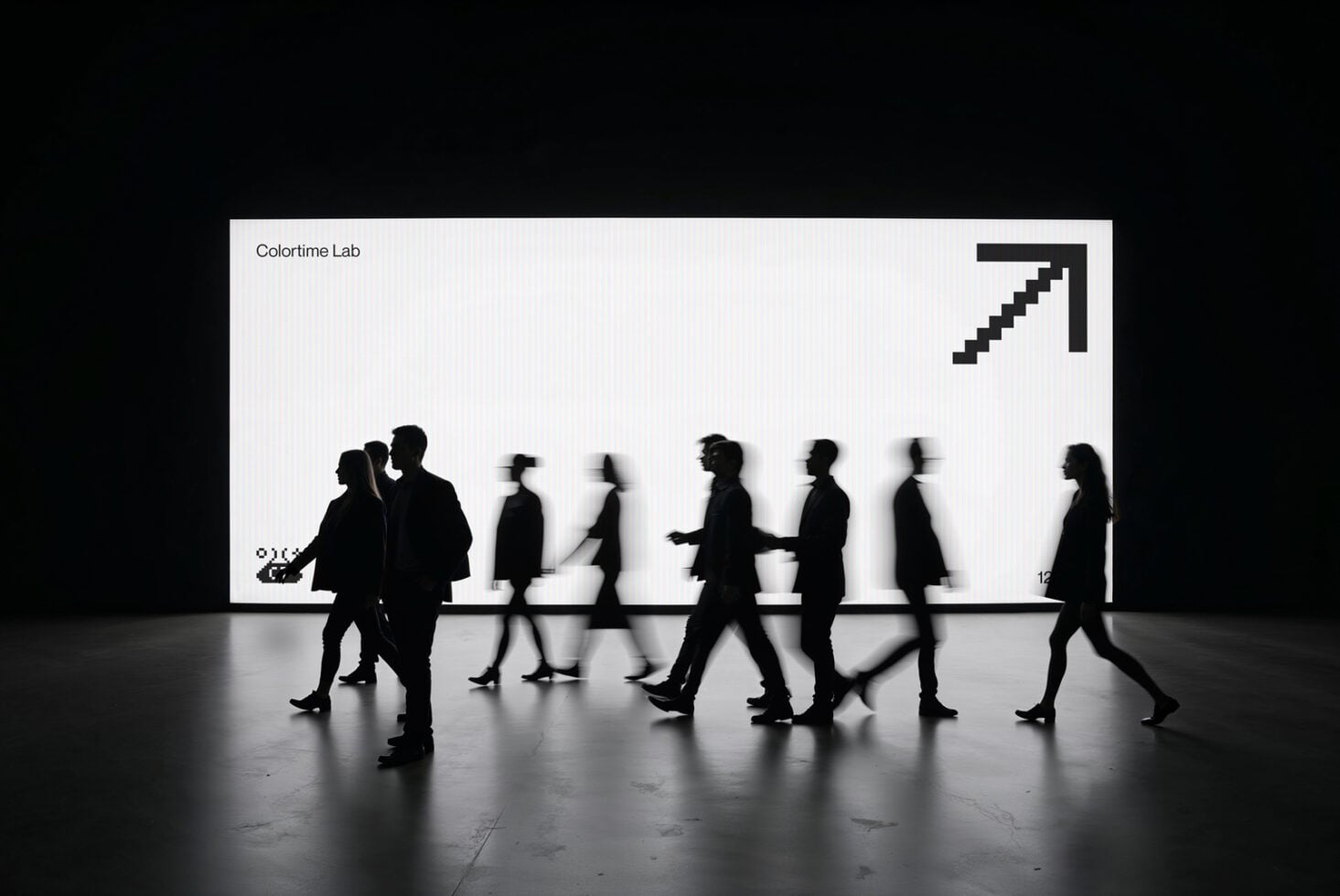 Moving crowd silhouettes in front of bright white display screen with upward arrow symbol