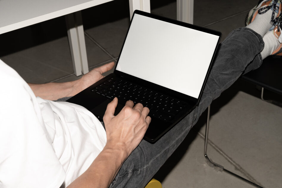 Laptop screen mockup blank display held open on lap with black keyboard