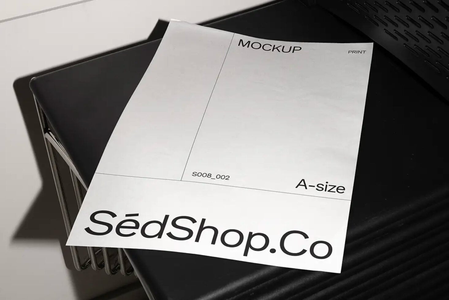 White A-size print mockup on black chair, clean minimalist studio setup