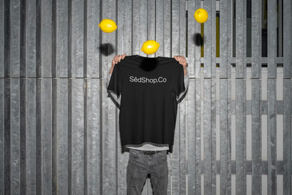Black t-shirt on headless figure with yellow lemons, vertical striped wall setting