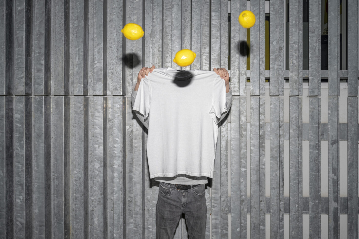 White t-shirt on figure with floating yellow lemons against striped wall backdrop
