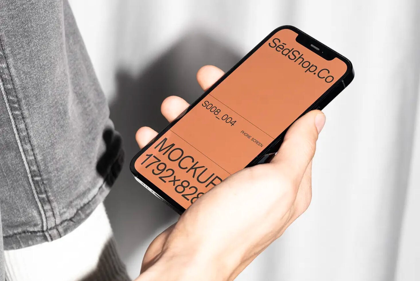 Hand holding iPhone mockup with peach screen displaying SedShop.Co branding