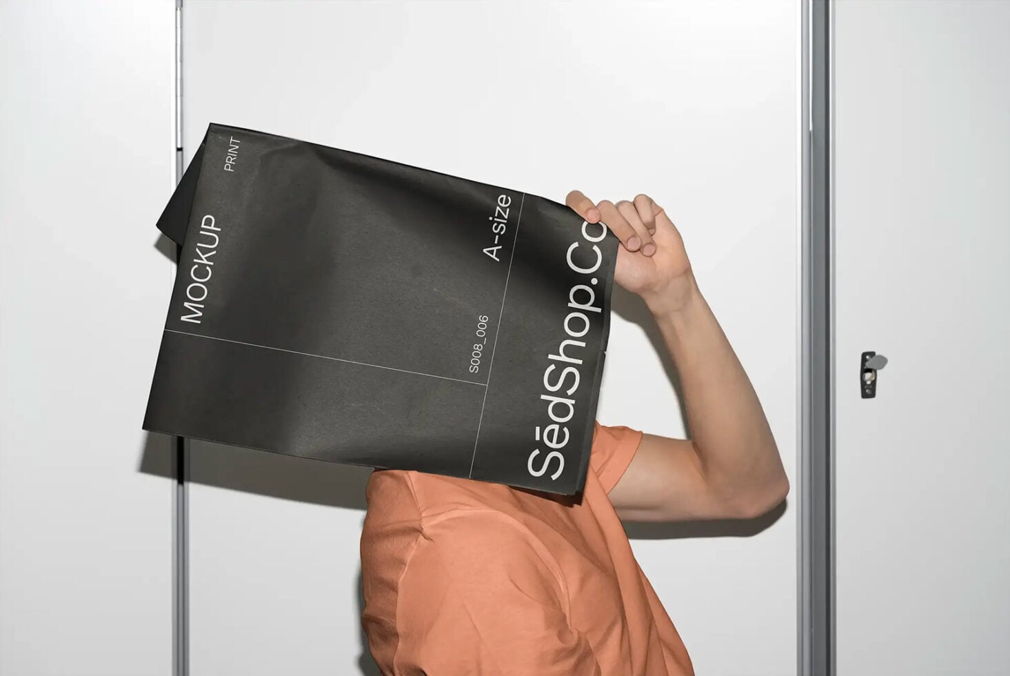 Person holding black A4 folder mockup with white text against white door frame background