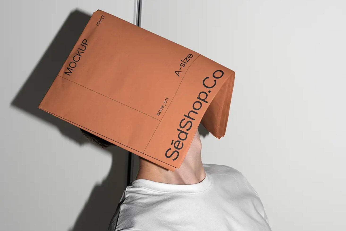 Person holding orange A2 mockup with SedShop.Co text above their head