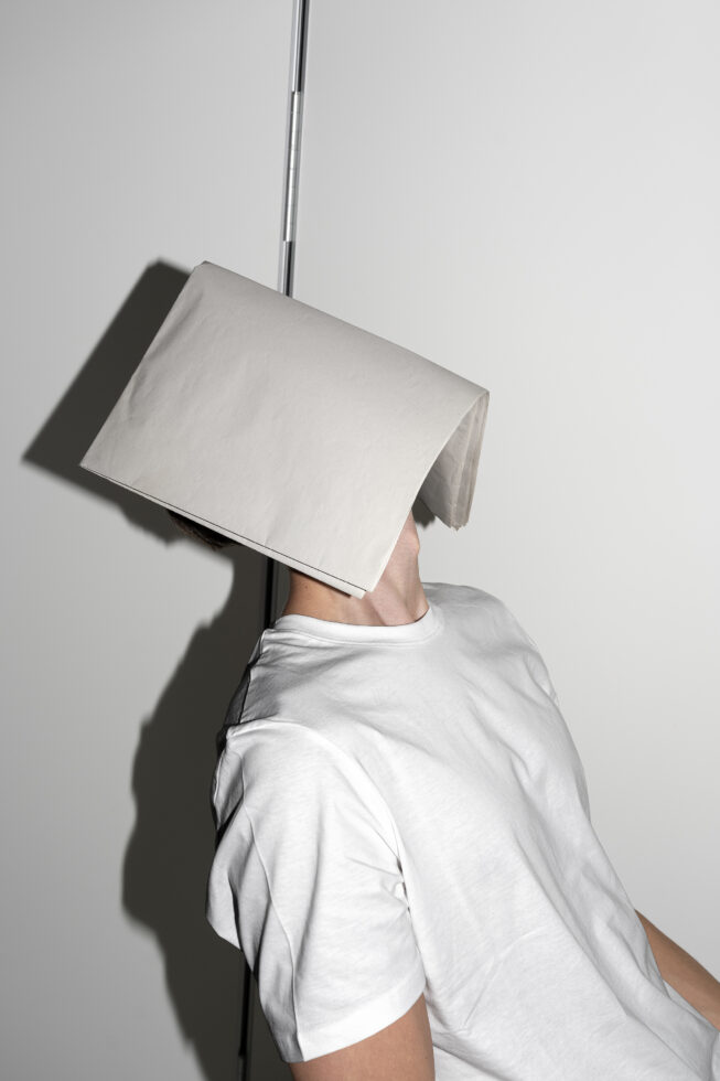 Person holding blank white A2 paper over their head on metal rod