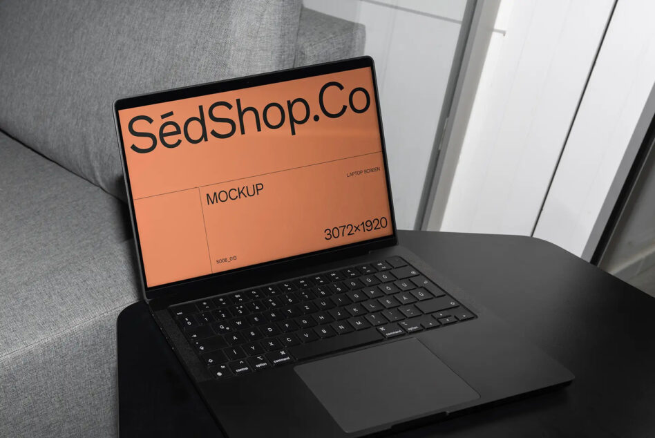Black laptop on couch showing SédShop branding with orange screen background