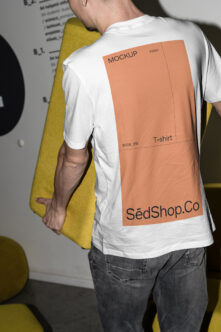 White tee with orange back print mockup, person holding yellow folder