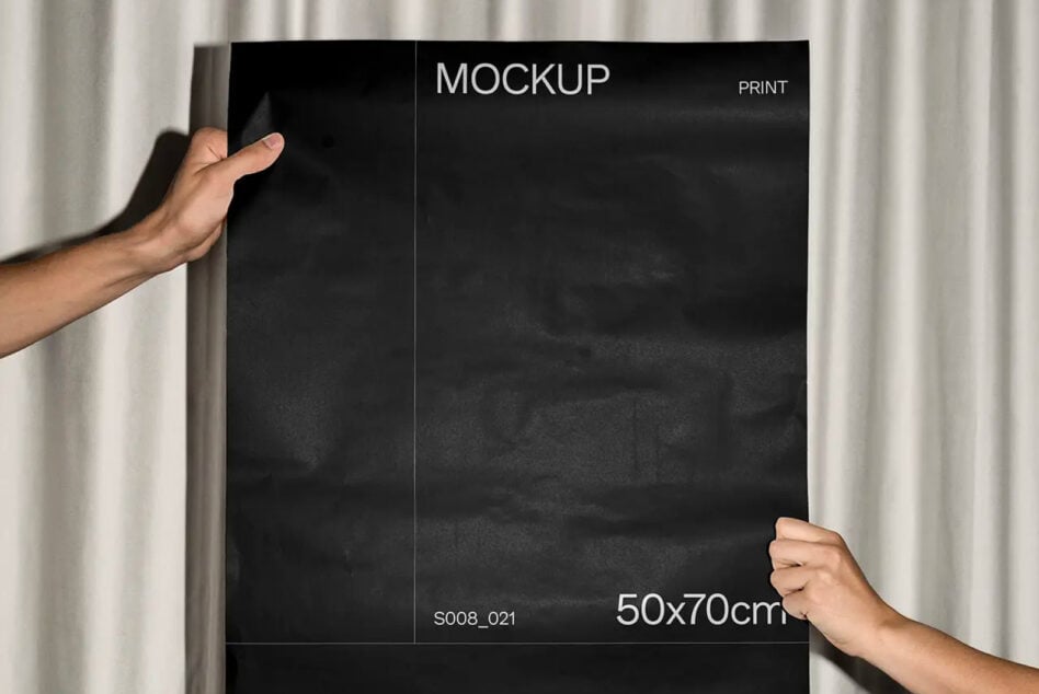 Hands holding black poster with white mockup text against cream curtain