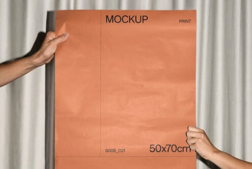 Hands holding large terracotta poster mockup against textured curtain