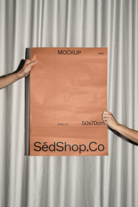 Hands holding terracotta poster with SédShop.Co branding against curtain