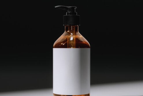 Amber glass pump bottle with white label on black background