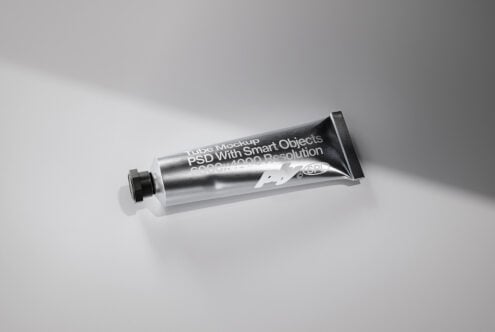 Metallic tube mockup with white label text overlay on gray backdrop