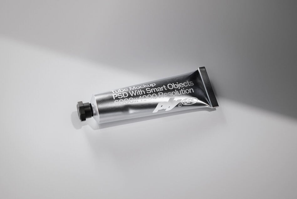Metallic tube mockup with white label text overlay on gray backdrop