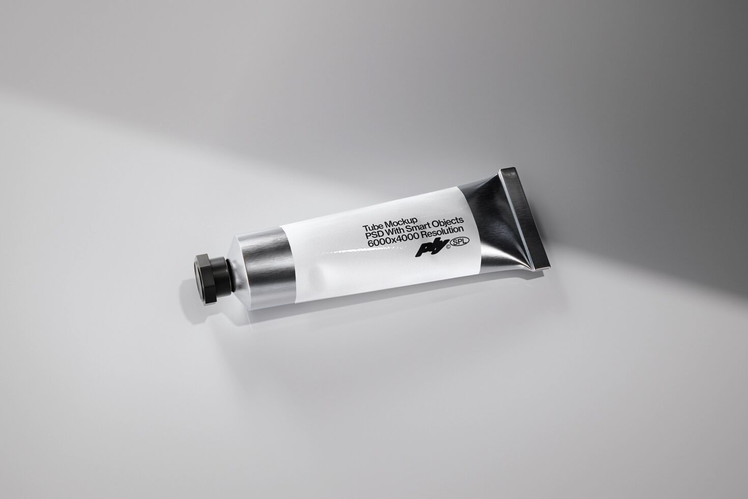White cosmetic tube with metallic cap lying on light gray surface