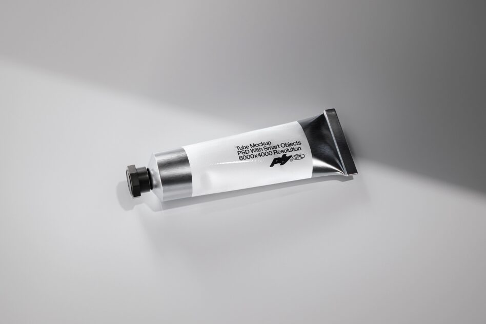 White cosmetic tube with metallic cap lying on light gray surface