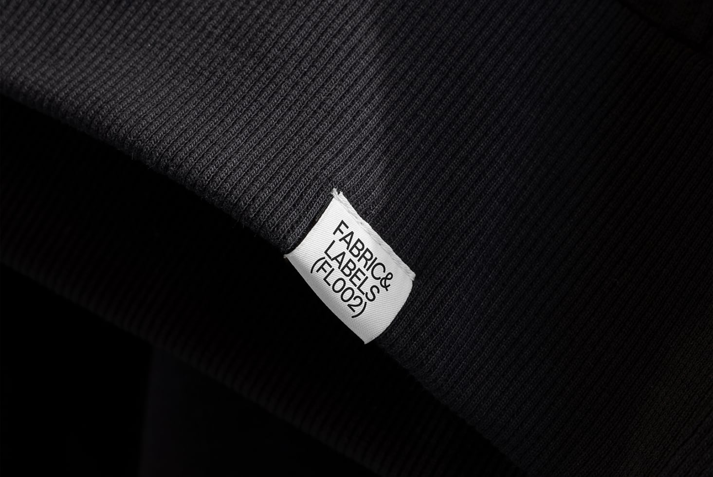 White woven label tag on dark ribbed fabric with clean typography view