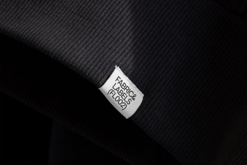 White woven label tag on dark ribbed fabric with clean typography view