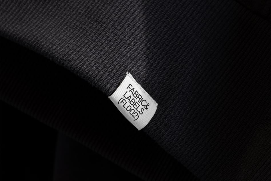 White woven label tag on dark ribbed fabric with clean typography view