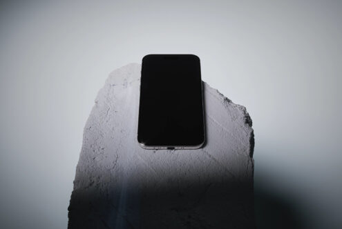 Smartphone on textured white concrete block against neutral backdrop