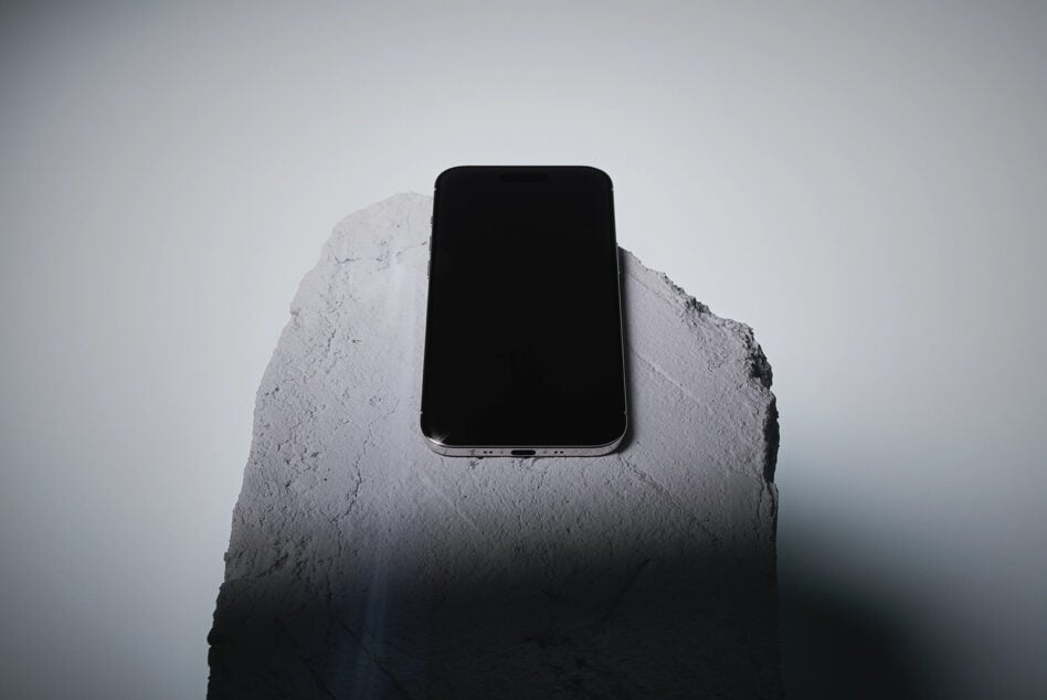 Smartphone on textured white concrete block against neutral backdrop